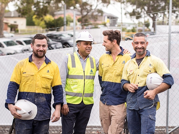 Workers at Australian contractor ADCO smile together while standing on site.