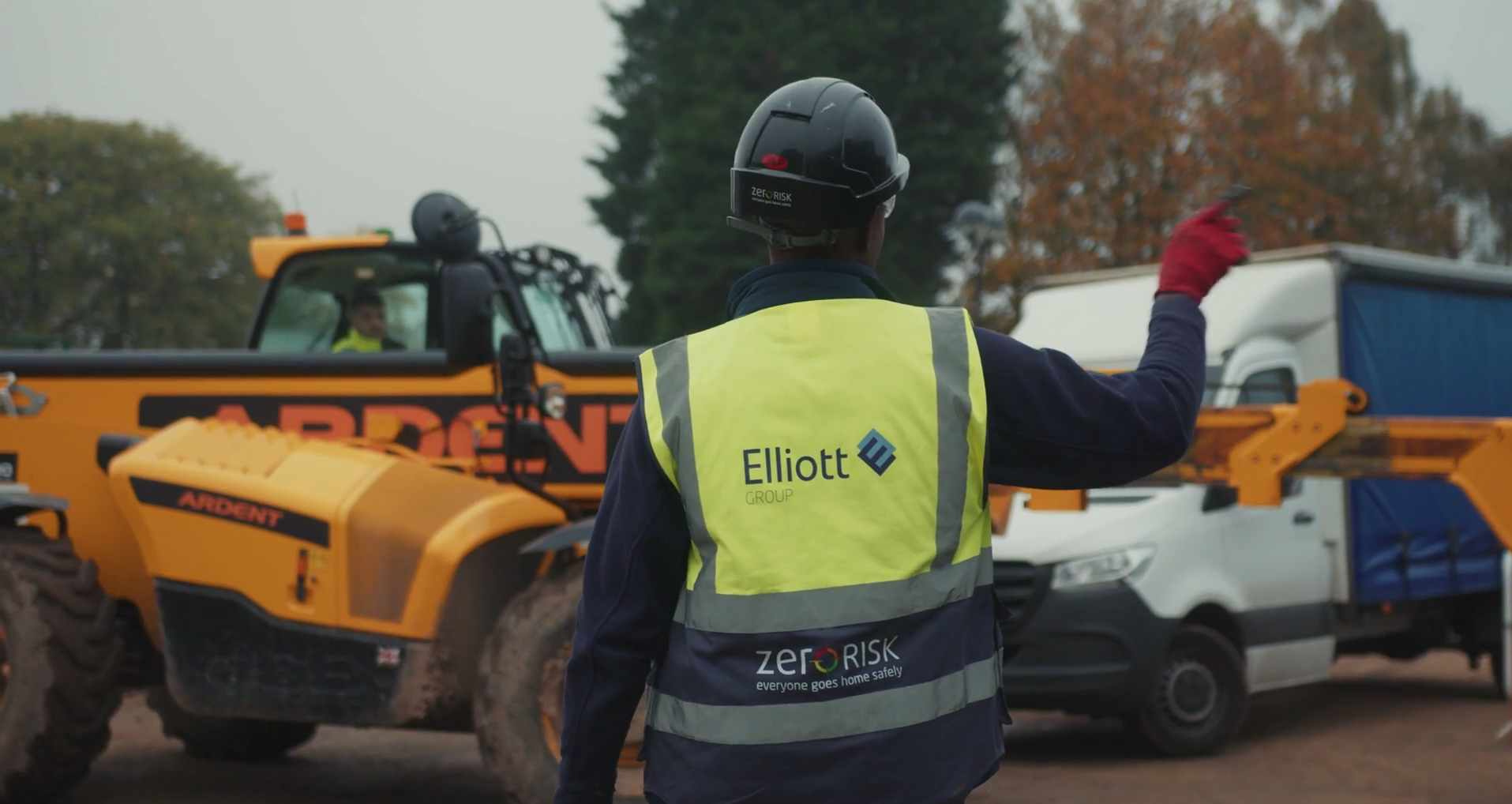 Back of an Elliott construction worker on site directing construction safety.