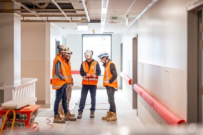 Group of Hawkins construction workers on the job site using HammerTech on a tablet for construction safety.